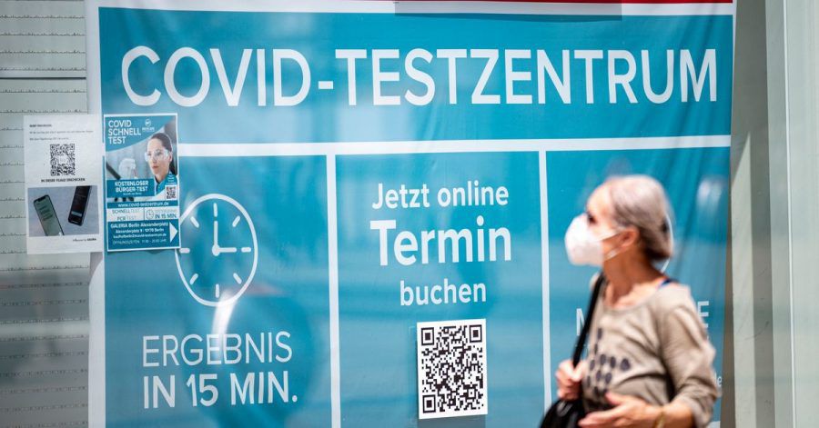 Eine Frau mit Maske läuft an einem Corona-Testzentrum am Berliner Alexanderplatz vorbei.