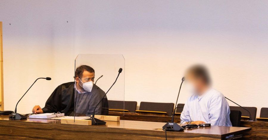 Ein Angeklagter sitzt im Gerichtssaal und hört seinem Anwalt zu.