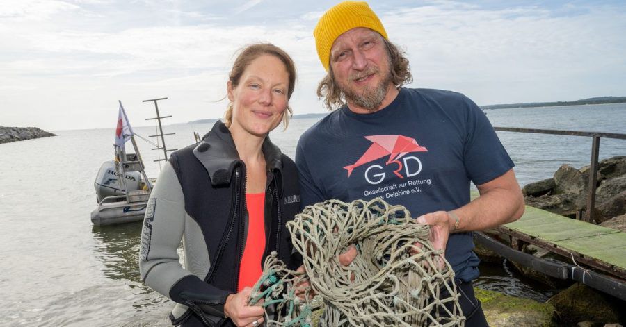Das Schauspieler-Paar Tessa Mittelstaedt (47) und Matthias Komm (54) steht vor einem Tauchgang in die Ostsee vor der Insel Rügen an der Tauchbasis Mukran mit einem Netz in der Hand da.