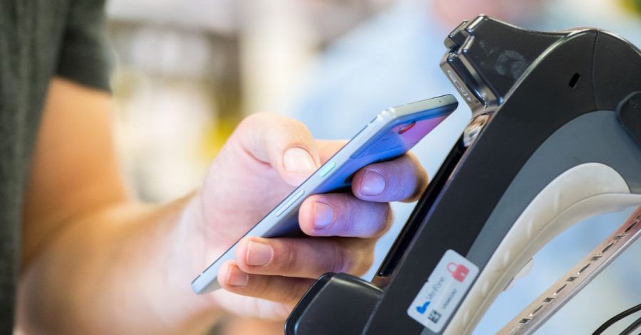 Ein Smartphone wird an ein Kassenterminal gehalten. Mit der entsprechenden App kann man so bezahlen.