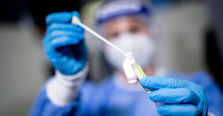 Eine Frau hält am Flughafen München in einem Covid-19 Testcenter die Probe von einem Rachenabstrich in den Händen. Politiker aus unterschiedlichen Parteien diskutieren, ob Coronatests weiterhin kostenlos für Alle sein sollen.