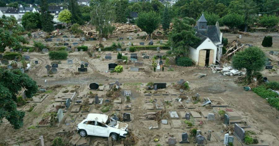 Ein Auto, das bei der Hochwasserkatastrophe auf den Friedhof geschwemmt worden ist, steht auf einem Grabfeld. Der Friedhof ist völlig zerstört.
