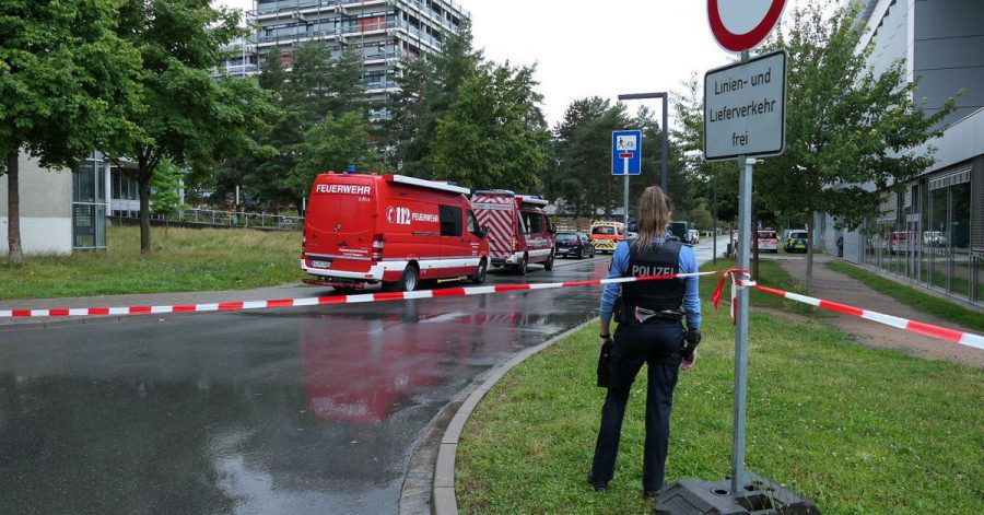 Eine Beamtin und Einsatzfahrzeuge der Feuerwehr auf dem Campus der TU Darmstadt.