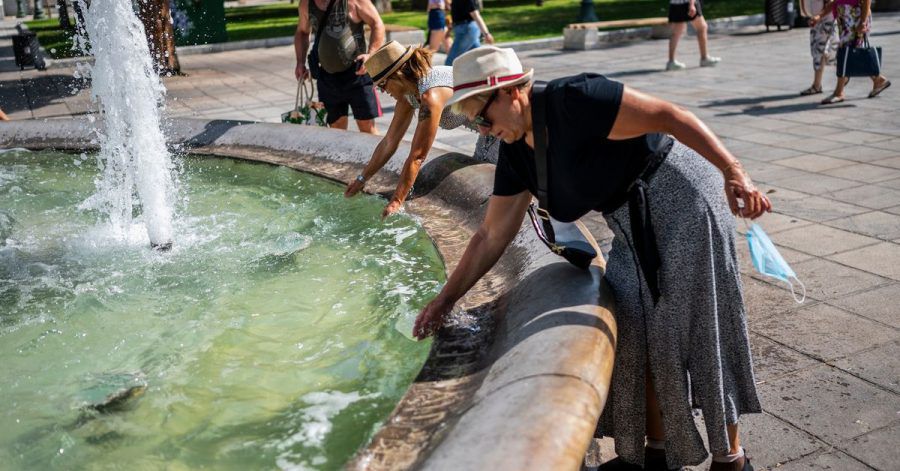 Menschen erfrischen sich bei Temperaturen über 40 Grad mit Wasser aus einem Brunnen auf dem Syntagma-Platz in Athen.