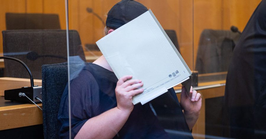 Zu Beginn des Prozesses im Missbrauchskomplex Münster sitzt die Mutter eines Opfers im Landgericht Münster und verdeckt ihr Gesicht mit einer Mappe.