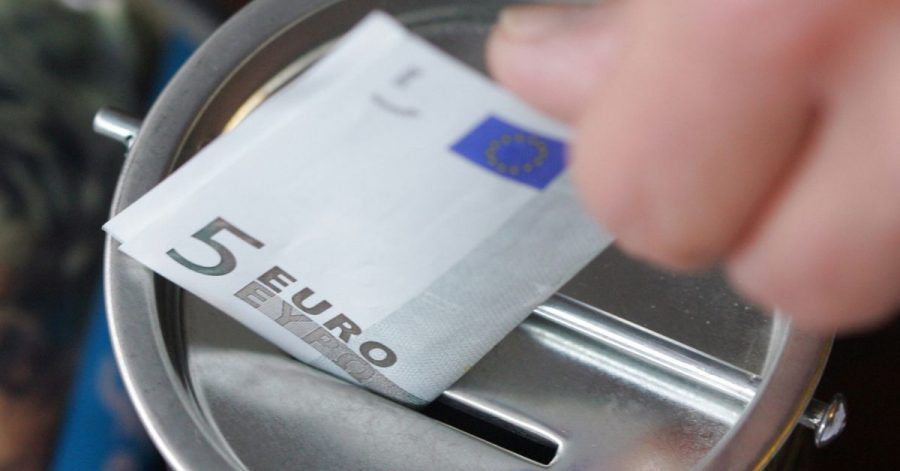 Ein Fünf-Euro-Schein wird in eine Spendendose gesteckt. Symbolbild