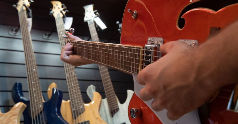 Ein Mann spielt in einem Gitarrenladen auf einer Linkshänder-Guitarre.