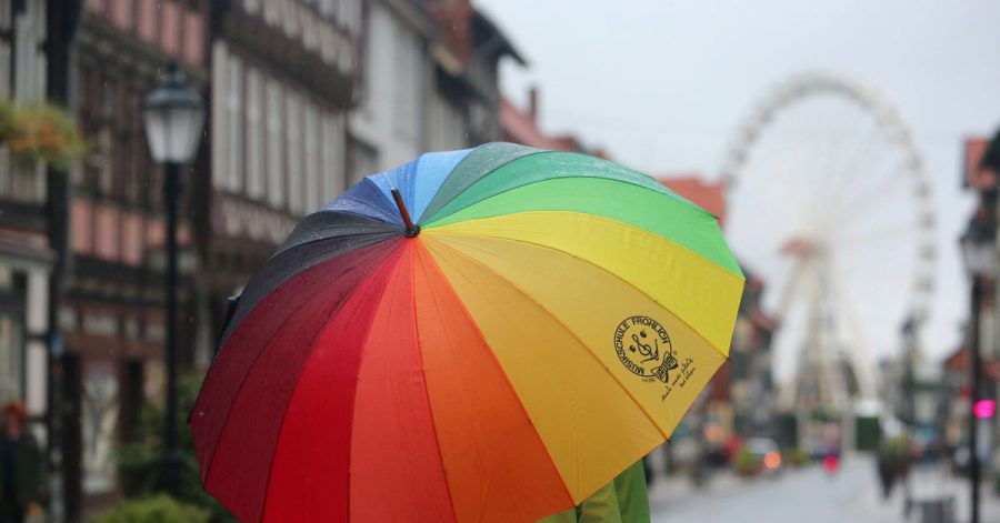 Passanten gehen bei Regenwetter durch die Fußgängerzone von Wernigerode in Sachsen-Anhalt.
