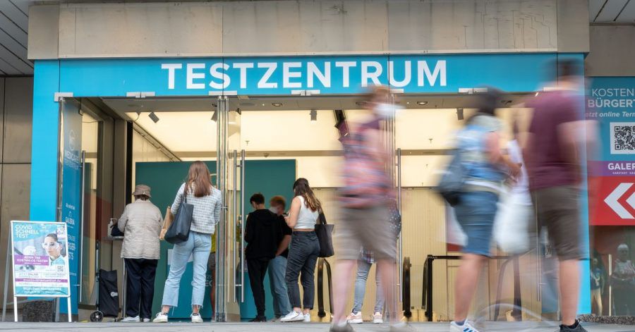 Passanten gehen an einem Corona-Testzentrum in der Fußgängerzone der Münchner Innenstadt vorbei.