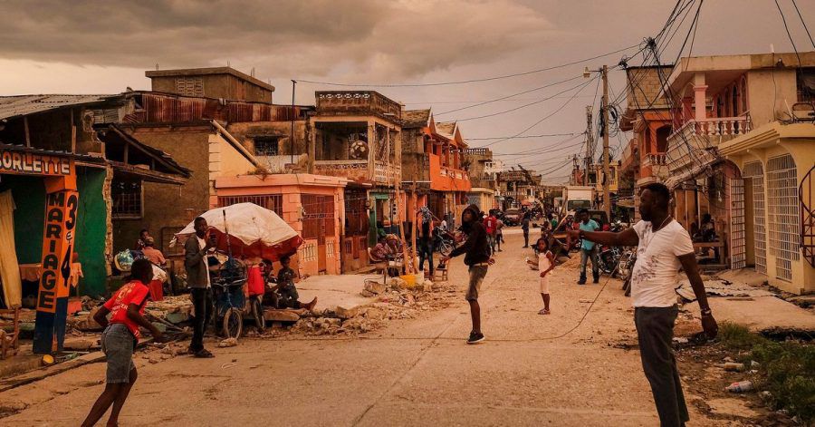 Anwohner stehen bei Sonnenuntergang auf einer Straße in Les Cayes, Haiti.