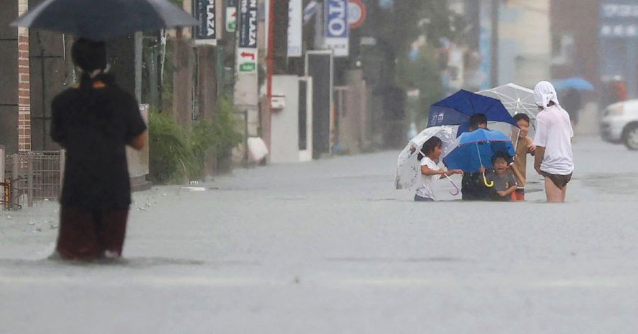 Menschen waten durch eine von starkem Regen überflutete Straße in Kurume, Präfektur Fukuoka, Westjapan.
