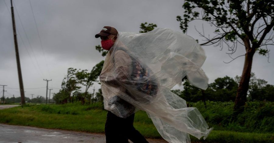 Ein Mann geht auf einer Straße nach Batabano in der kubanischen Provinz Mayabeque. Er versucht sich mit Plastikplanen gegen den von Hurrikan Ida verursachten Regen zu schützen.