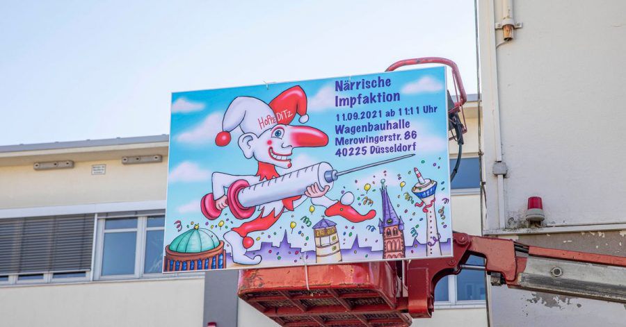 "Närrische Impfaktion" steht auf einem Schild an der Wagenbauhalle in Düsseldorf.