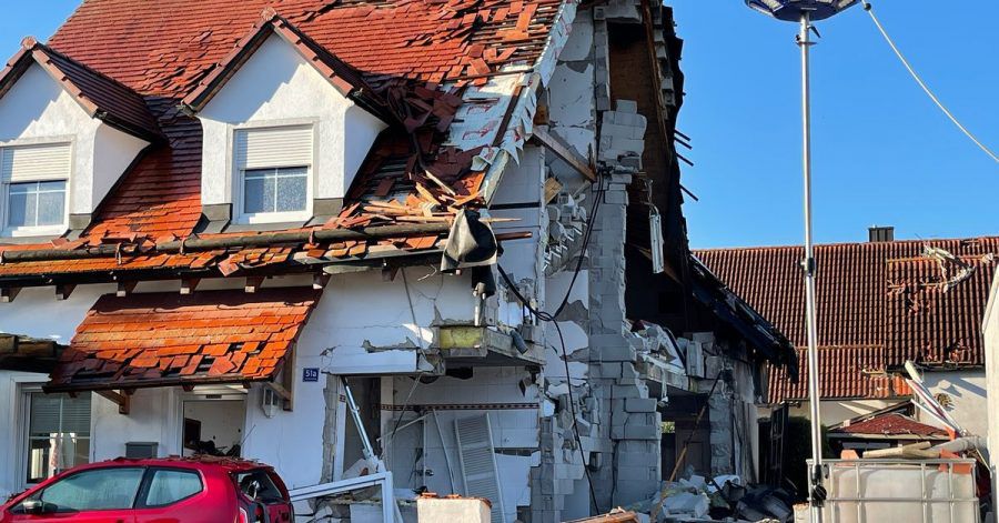 Nach der Explosion eines Wohnhauses ist das Nachbarhaus von Beschädigungen schwer gezeichnet.