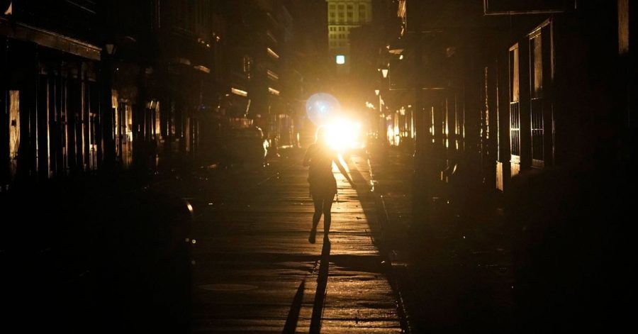 Eine Frau geht im Scheinwerferlicht eines patrouillierenden Polizeiwagens über die Bourbon Street in New Orleans.