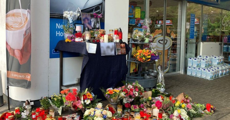Menschen haben Blumen und Kerzen am Tatort abgelegt.