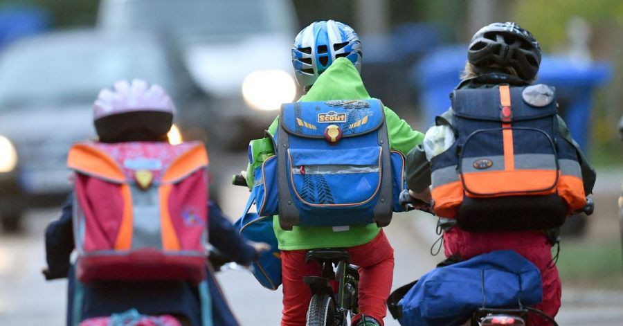Kinder sind auf einer Straße mit dem Fahrrad unterwegs zur Schule. Symbolbild