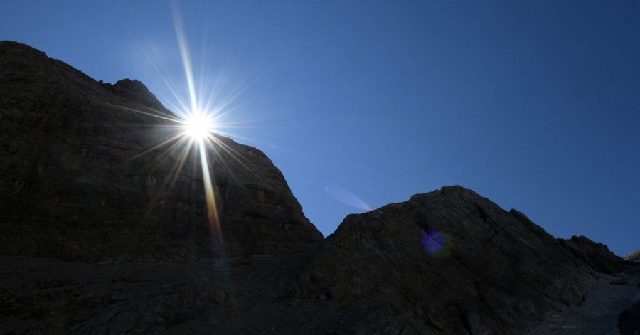 Die Sonne kommt am Morgen hinter einem Felsen im Watzmannkar (Bayern) hervor.