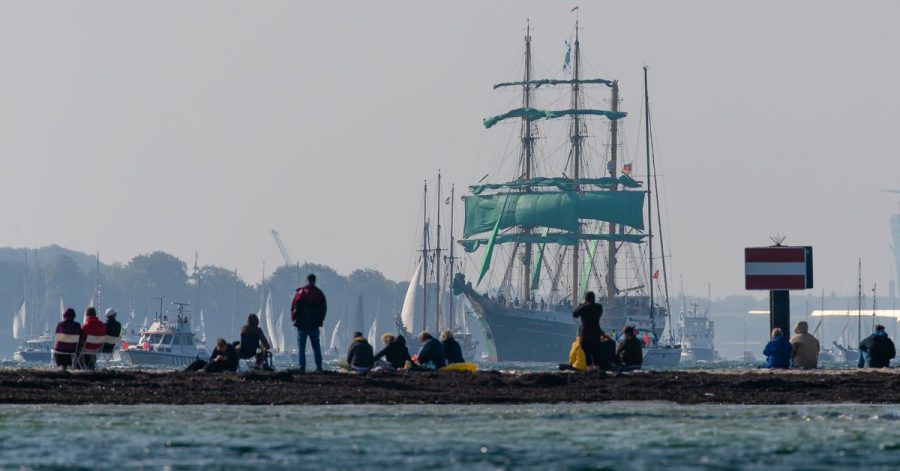 Zuschauer beobachten am Falkensteiner Strand die Windjammerparade der Kieler Woche.