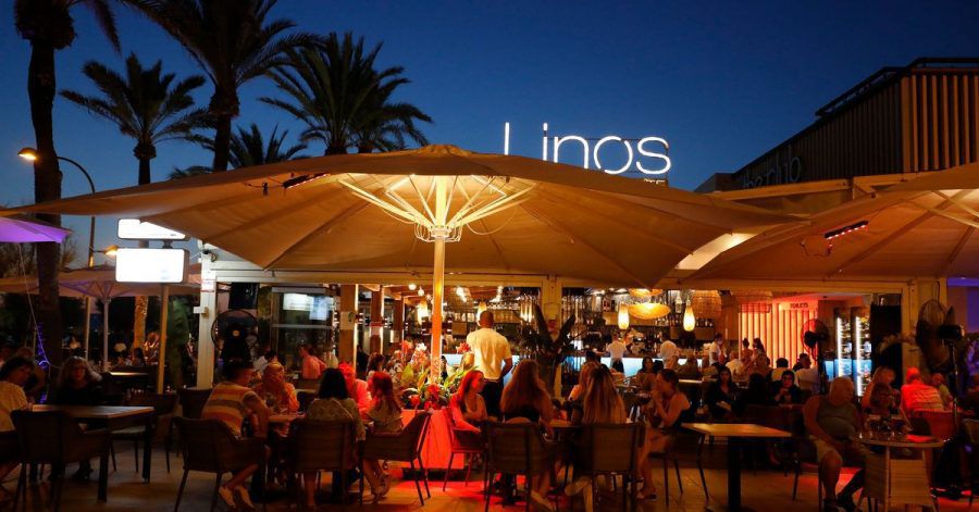 Menschen sitzen in einer Bar an der Strandpromenade von Palma.