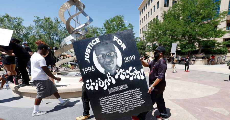 Demonstranten tragen während einer Kundgebung vor dem Polizeirevier wegen des Todes von Elijah McClain ein Plakat mit dessen Bild.