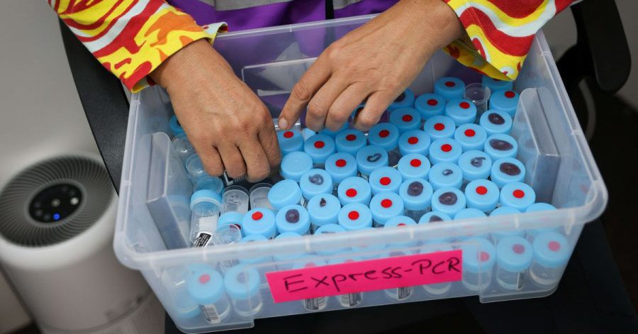 Eine Mitarbeiterin sortiert noch unbenutzte Behälter für einen PCR-Gurgeltest in einem Testcenter für Corona-Schnelltests (Antigentest) und Corona-PCR-Tests.