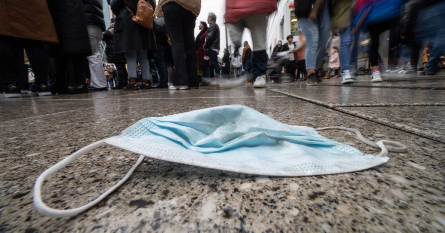 Ein verlorener Mund-Nasen-Schutz liegt auf dem nassen Pflaster von Frankfurts zentraler Einkaufsmeile. Der seit gut zwei Wochen anhaltende Anstieg der Sieben-Tage-Inzidenz in Deutschland setzt sich fort.