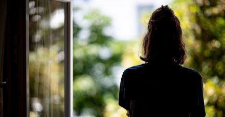 Eine Frau steht in ihrer Wohnung an einem Fenster. (Archivbild)