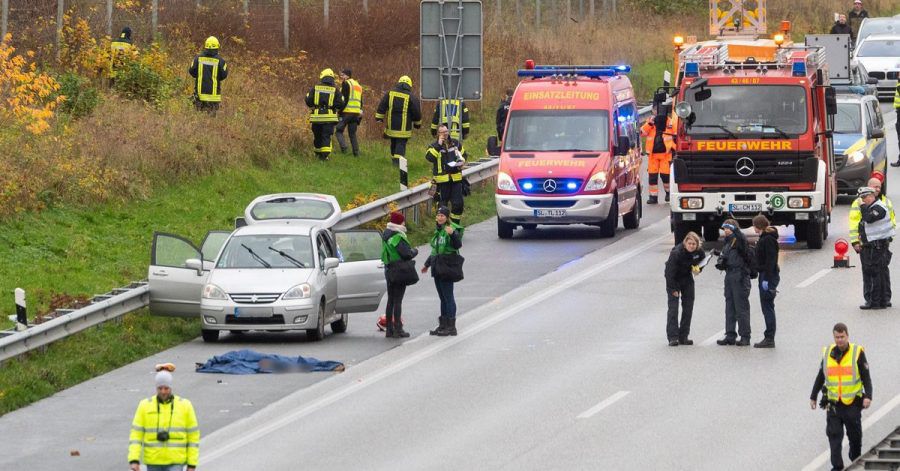 Polizisten und Rettungskräfte stehen neben dem Leichnam der jungen Frau auf der Autobahn 7.