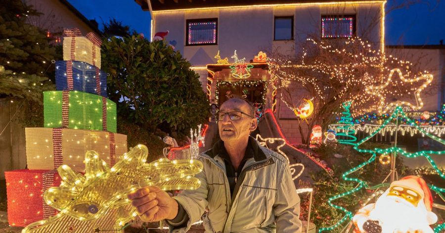 Rentner Josef Johann baut vor seinem Haus im Moseldorf Klotten bunte leuchtende Weihnachtsdekoration auf.