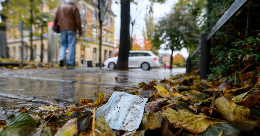 Ein Mundschutz liegt zwischen herbstlich gefärbten Blättern auf dem Boden der Altstadt Pirna im Landkreis Sächsische Schweiz-Osterzgebirge.