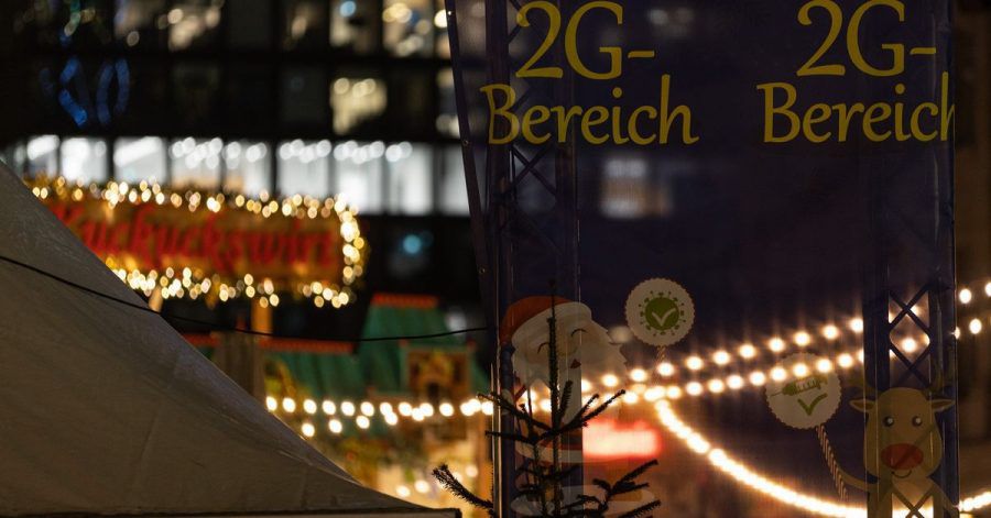 Ein Hinweis auf einen 2G-Bereich hängt auf dem Frankfurter Weihnachtsmarkt zwischen Lichterketten.