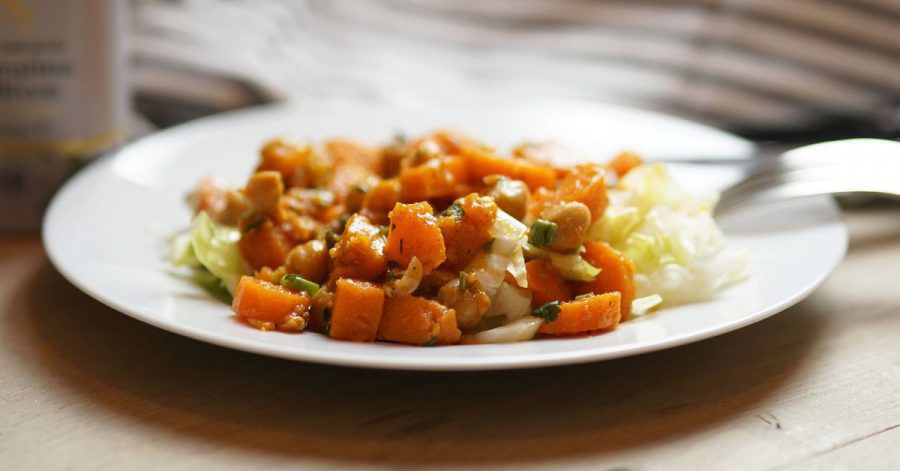 Der herzhafte Salat aus Süßkartoffeln, Kichererbsen und Möhren wird auf Eisbergsalat angerichtet.