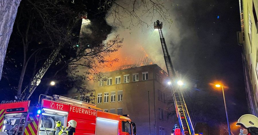 Einsatzkräfte der Feuerwehr löschen das brennende Schulgebäude.