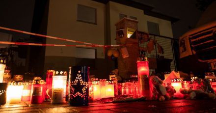 Kerzen brennen auf dem Gehweg vor dem Einfamilienhaus Königs Wusterhausen, wo Polizisten eine Familie tot aufgefunden hatten.