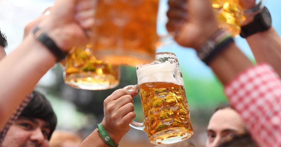 Besucher prosten sich in einem Bierzelt mit Biergläsern zu.