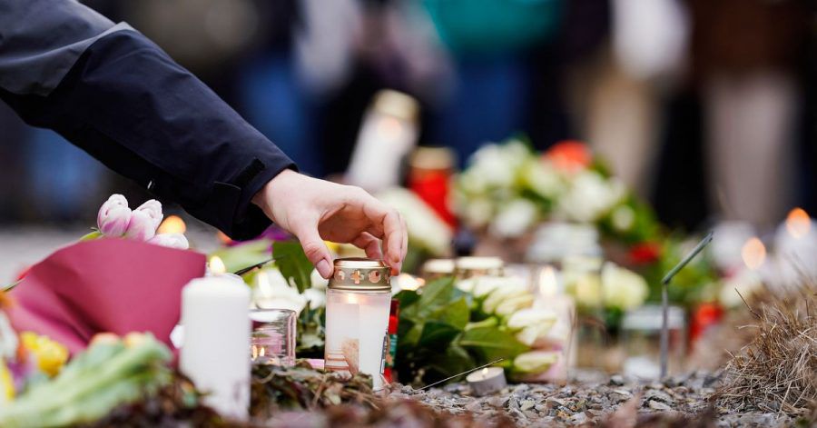 Menschen haben vor einem Gebäude der Heidelberger Universität Blumen und Kerzen niederlegt.