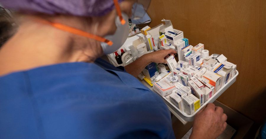 Eine Krankenpflegerin nimmt Medikamente von einem Ständer.