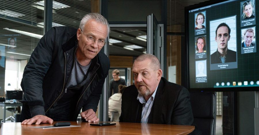 Daniel Huberty (Stephan Kampwirth, Bildschirm) gibt Max Ballauf (Klaus J. Behrendt, l) und Freddy Schenk (Dietmar Bär) seine Forderungen durch.