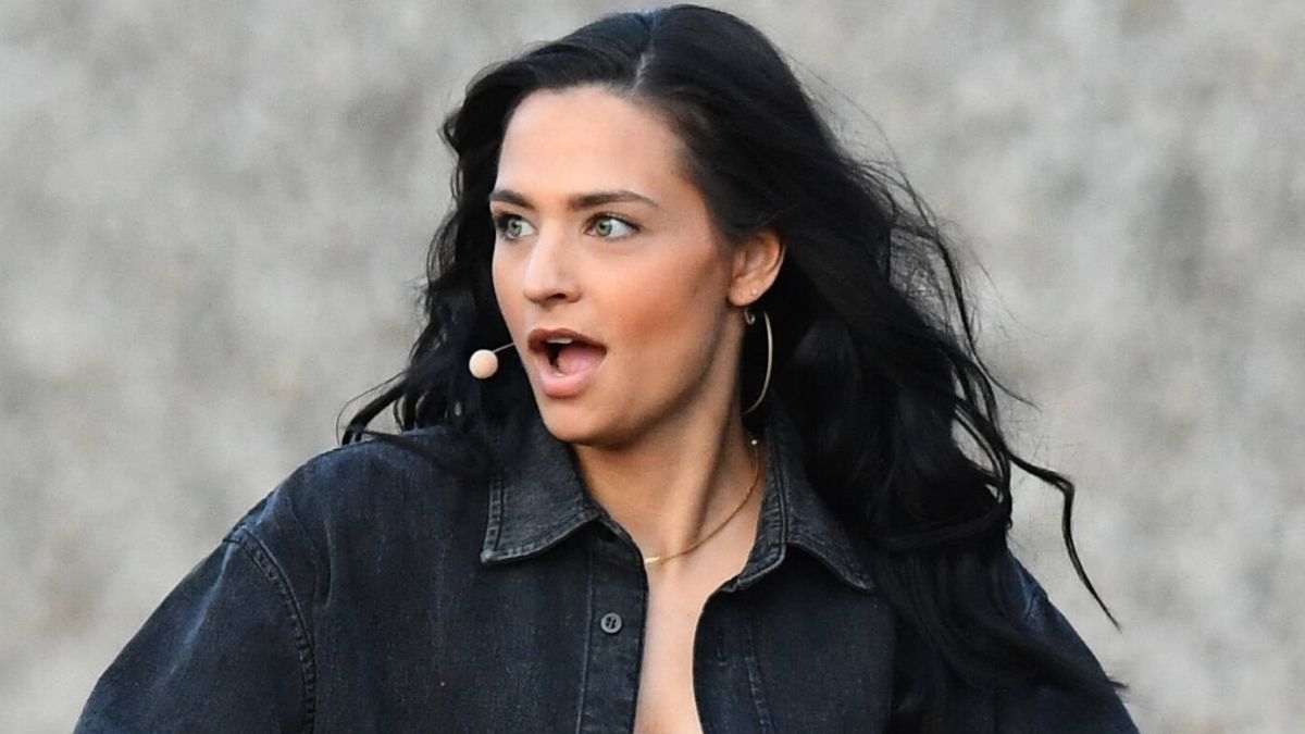 Amira Pocher in schwarzer Bluse reißt erstaunt den Mund auf