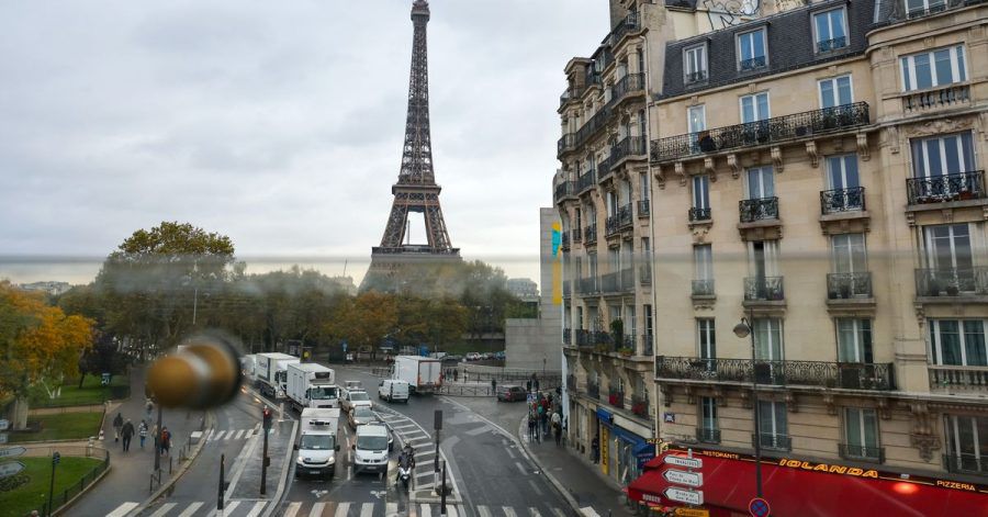 Aus dem Fenster der Pariser Metro ist hinter Wohnhäusern der Eiffelturm zu sehen - samt des üblichen Straßenrkehrs.