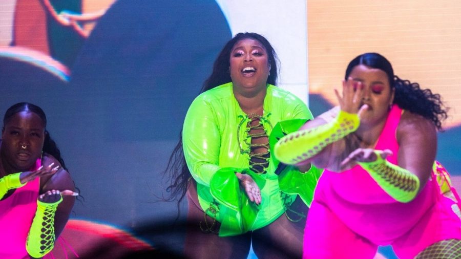 Lizzo in neongrünem Outfit und zwei Tänzerinnen in Pink