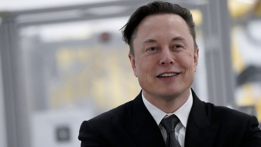 Elon Musk im dunklen Anzug lächelt zuversichtlich