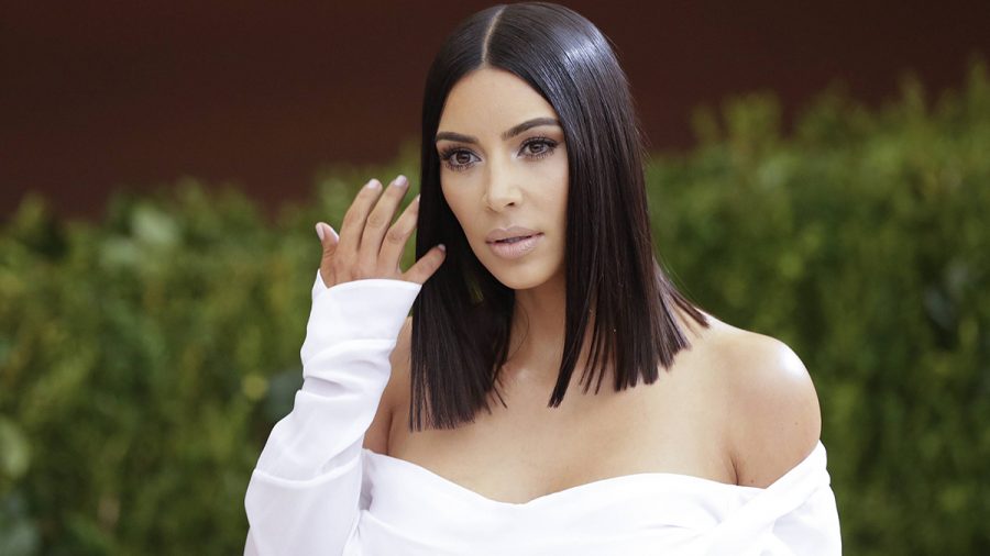 Kim Kardashian hält auf dem roten Teppich die Hand hoch