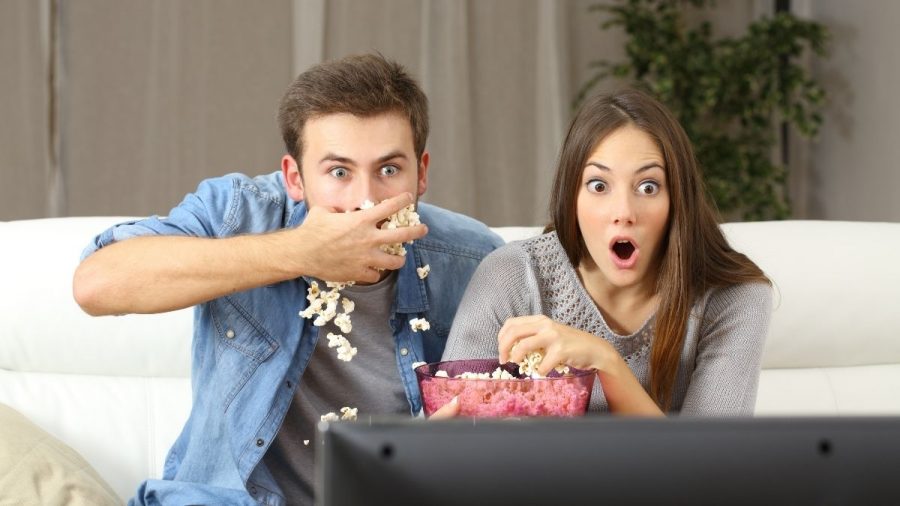 Paar vor Fernseher schockiert mit Popcorn.