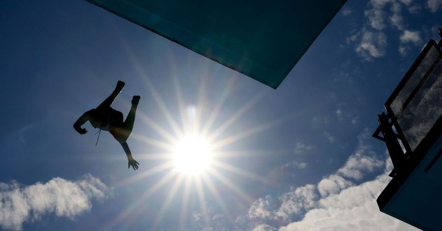 Ein Mann springt im Freibad vom Zehn-Meter-Turm.