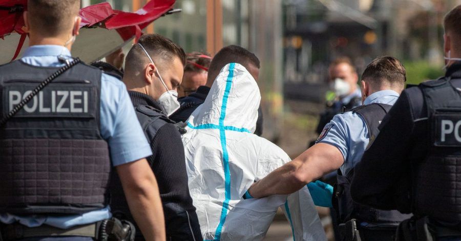 Polizisten führen den mutmaßlichen Täter ab. Der Mann soll in einer Regionalbahn mit einem Messer auf Reisende eingestochen haben.