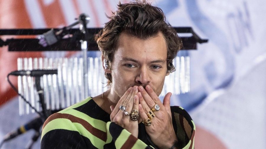 Harry Styles wirft im gestreiften Outfit Kusshände von der Bühne.