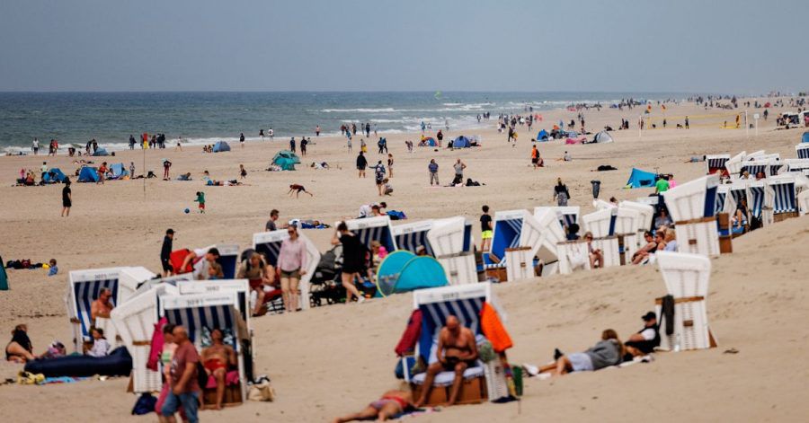 Besucher der Insel Sylt liegen in der strahlenden Sonne am Strand.