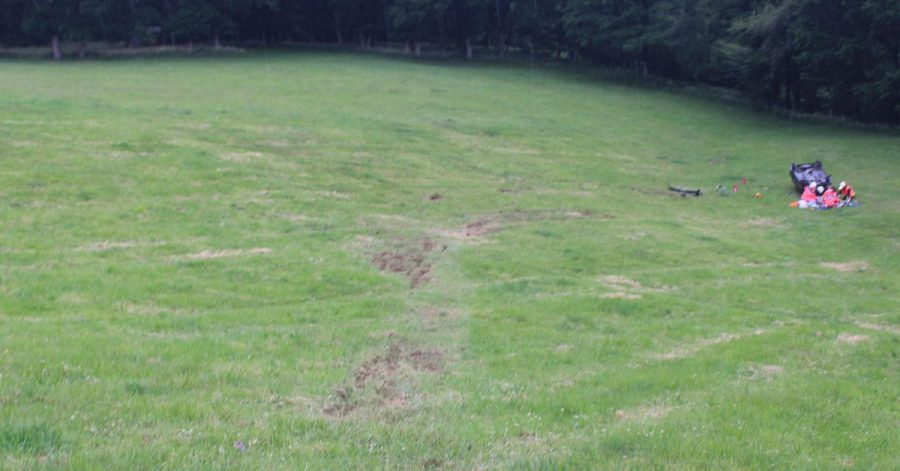 Eine Unfallspur führt auf einer Wiese zu einem verunglückten Wagen.